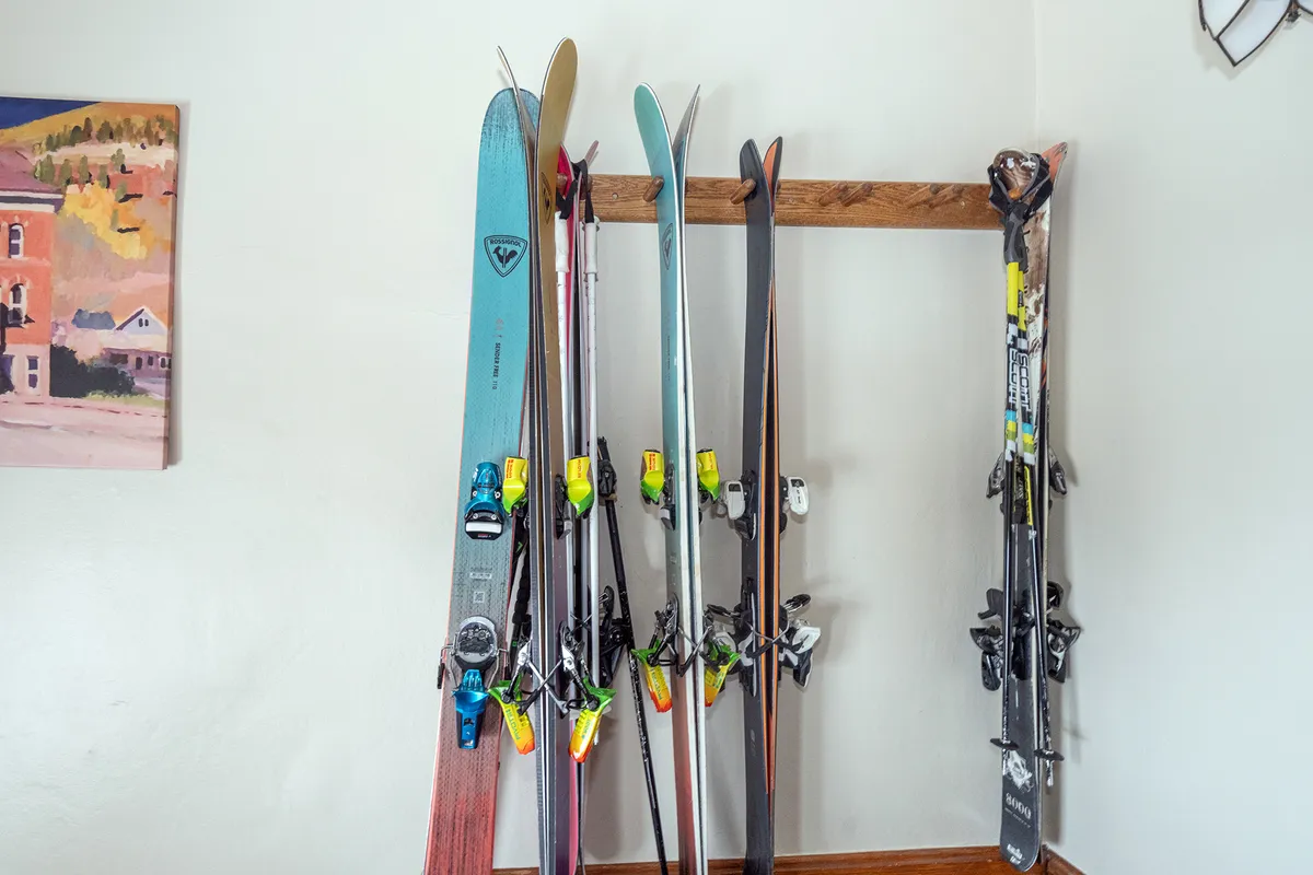 The scene highlights skis and ski poles neatly stored against the wall, with surrounding wall art contributing to a sense of mountain adventure. The space is clearly designed for gear storage, making it easy to prepare for the slopes or unpack after outdoor activities.