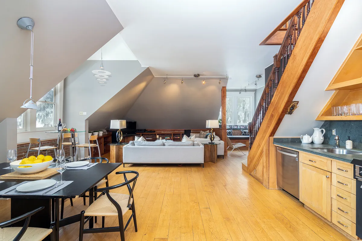 A contemporary space showing the seamless flow from dining area to sofa lounge and kitchen counter. The setting suggests a comfortable, sociable environment for both relaxed evenings and lively gatherings.