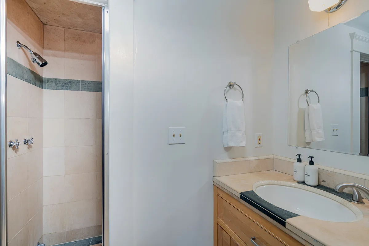 A modern, spa-inspired bathroom featuring a glass-enclosed shower area, a sleek sink, and a well-lit mirror. The design is clean, calming, and conducive to après-ski relaxation and self-care routines.